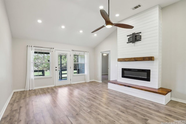 unfurnished living room with visible vents, a large fireplace, baseboards, wood finished floors, and a ceiling fan