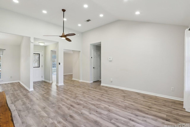 unfurnished living room featuring light wood finished floors, visible vents, baseboards, and lofted ceiling