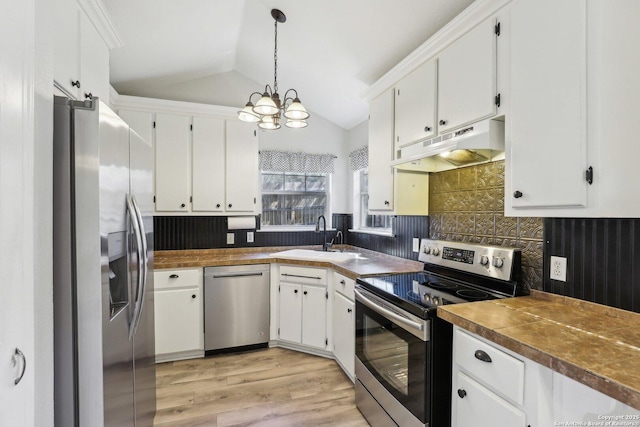 kitchen with under cabinet range hood, lofted ceiling, stainless steel appliances, white cabinetry, and a sink