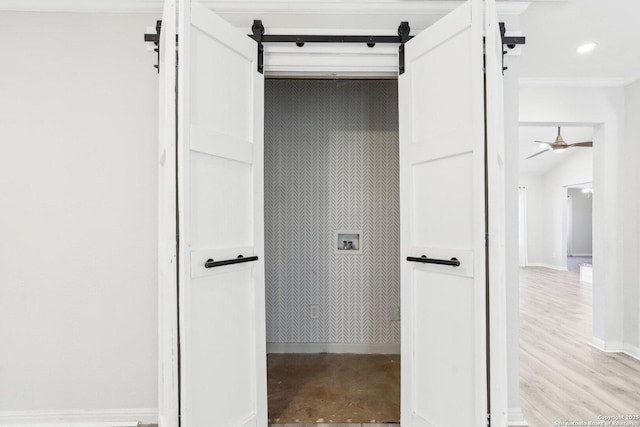 interior space with hookup for a washing machine, a barn door, baseboards, ceiling fan, and laundry area