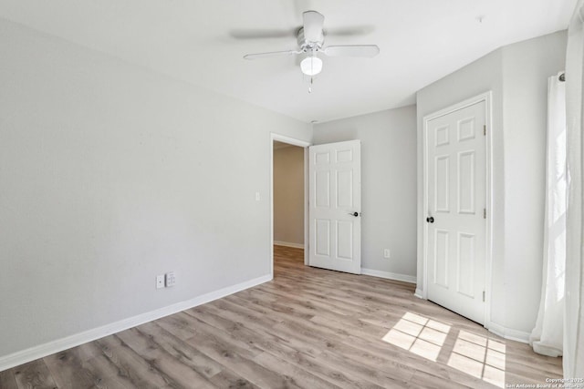 unfurnished bedroom with multiple windows, a ceiling fan, baseboards, and wood finished floors