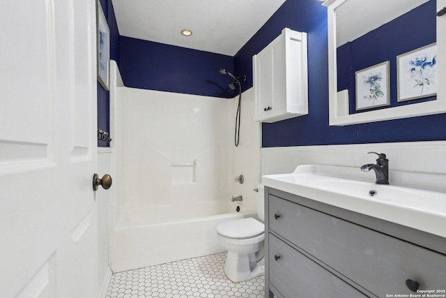 bathroom with tile patterned floors, a wainscoted wall, toilet, vanity, and shower / bathtub combination