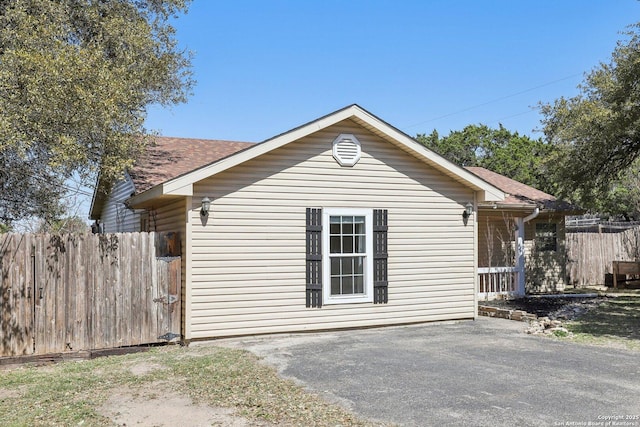 view of property exterior with a patio area, a shingled roof, and fence