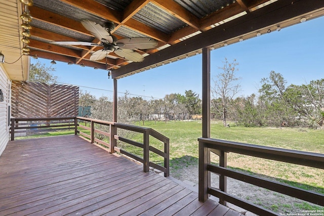 wooden terrace featuring a ceiling fan and a lawn