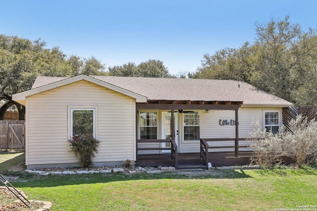 single story home featuring a front yard, a ceiling fan, covered porch, and a shingled roof