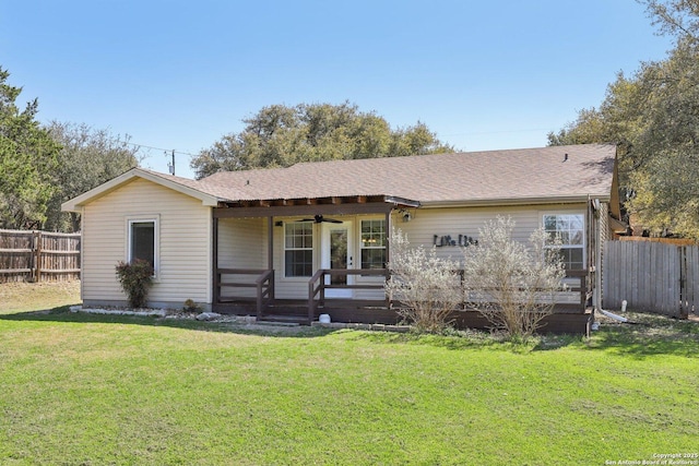 view of front of home with a shingled roof, a front yard, fence, and ceiling fan