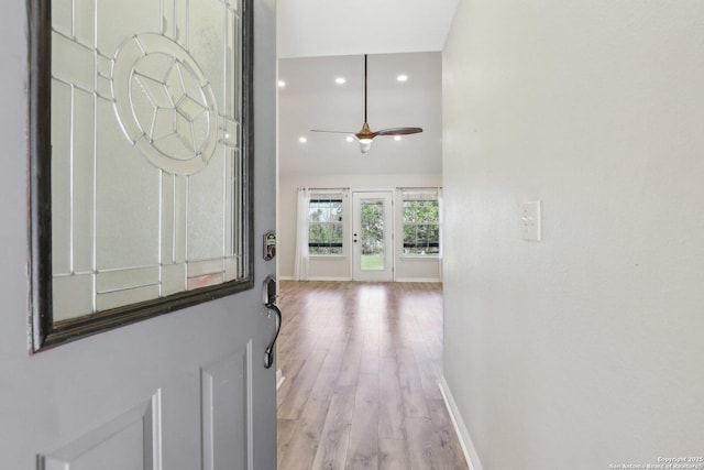 interior space featuring a ceiling fan, wood finished floors, baseboards, a high ceiling, and recessed lighting