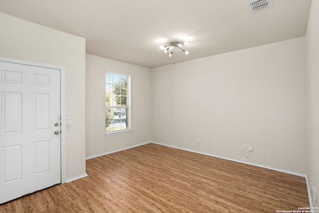 spare room featuring visible vents, light wood-type flooring, and baseboards