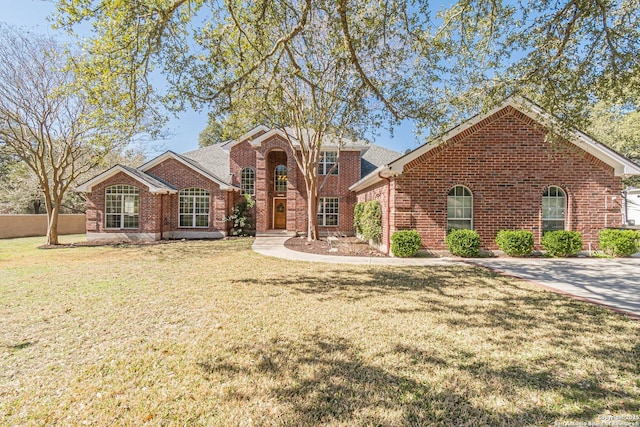 traditional-style home featuring brick siding, a front yard, and roof with shingles