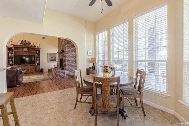 dining room featuring visible vents, a ceiling fan, arched walkways, light tile patterned floors, and baseboards