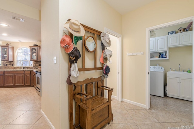 hallway with a sink, visible vents, washer / dryer, and light tile patterned flooring