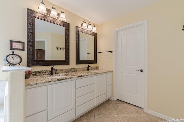 bathroom with tile patterned flooring, double vanity, baseboards, and a sink