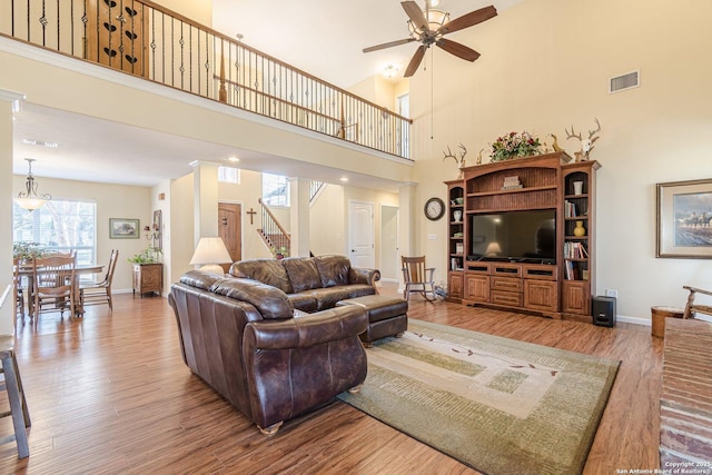 living room featuring visible vents, a ceiling fan, wood finished floors, stairway, and baseboards