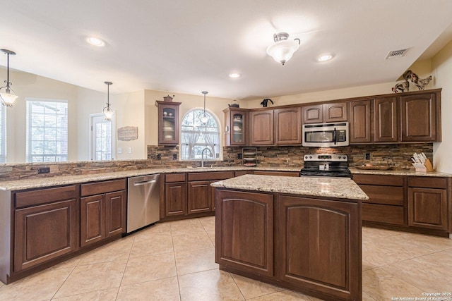 kitchen featuring visible vents, tasteful backsplash, appliances with stainless steel finishes, a peninsula, and glass insert cabinets