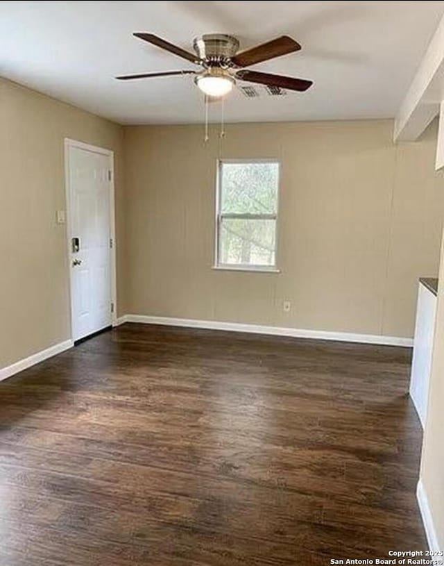 spare room with dark wood finished floors, ceiling fan, and baseboards