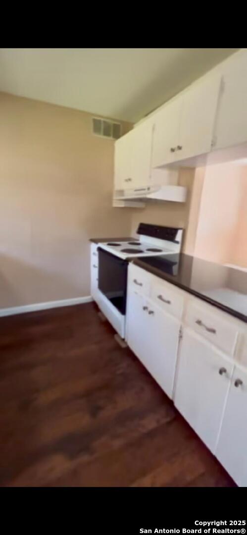 kitchen featuring visible vents, dark wood-style floors, white range with electric stovetop, exhaust hood, and white cabinets