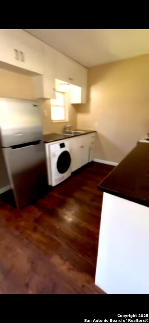 kitchen with a sink, washer / clothes dryer, dark wood-style floors, and freestanding refrigerator