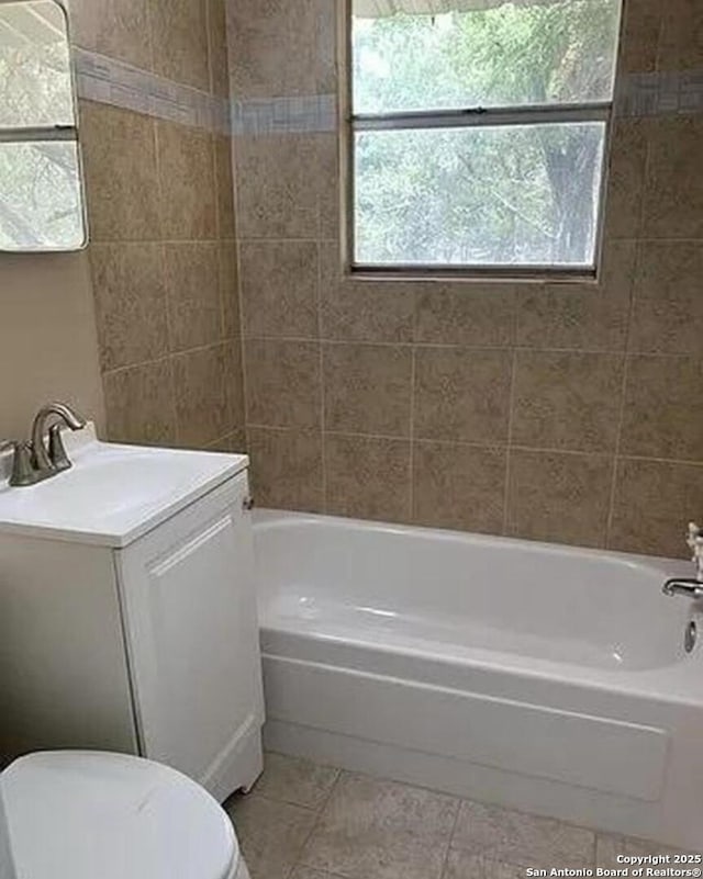 bathroom with tile patterned floors, toilet,  shower combination, and vanity