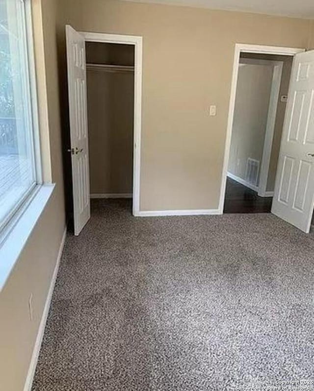 unfurnished bedroom featuring carpet flooring, visible vents, baseboards, and a closet