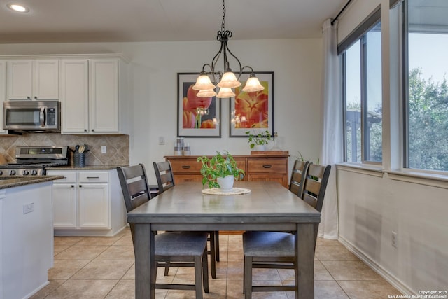 dining area with light tile patterned flooring, baseboards, a wealth of natural light, and a chandelier