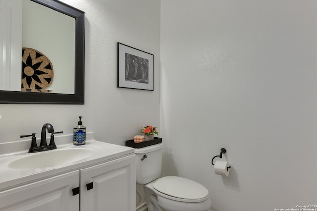 half bathroom with vanity and toilet