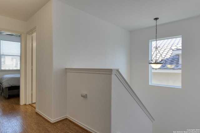 hall featuring wood finished floors, an upstairs landing, and baseboards