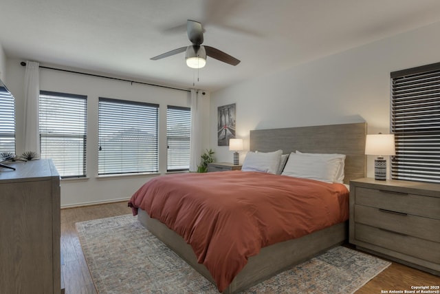 bedroom with ceiling fan, baseboards, and wood finished floors