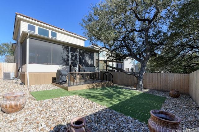 view of yard featuring central AC, a fenced backyard, and a sunroom