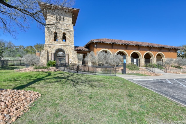 mediterranean / spanish-style house featuring fence, uncovered parking, stucco siding, an outdoor fireplace, and stone siding