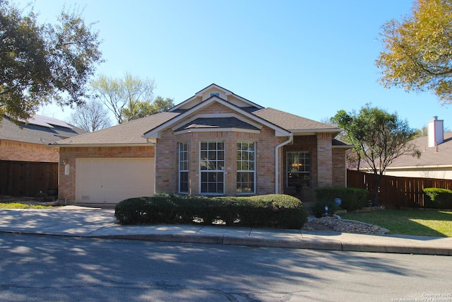 ranch-style house with concrete driveway, an attached garage, fence, and brick siding