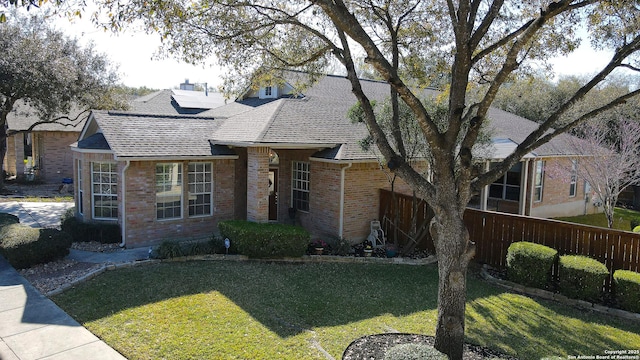 view of front of house with brick siding, a front yard, and fence