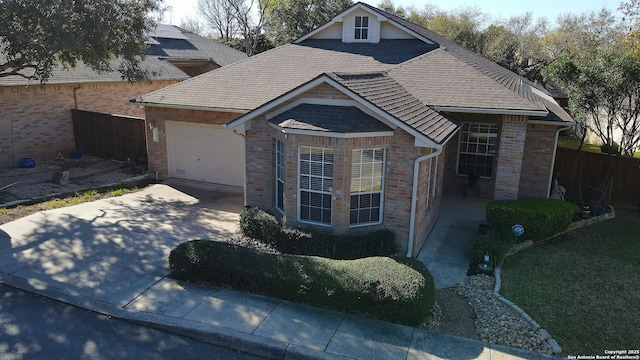 view of front of house featuring fence, roof with shingles, concrete driveway, a garage, and brick siding