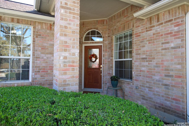 property entrance with brick siding and a shingled roof