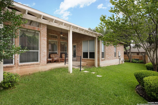 back of house featuring fence, a patio area, a lawn, a ceiling fan, and brick siding