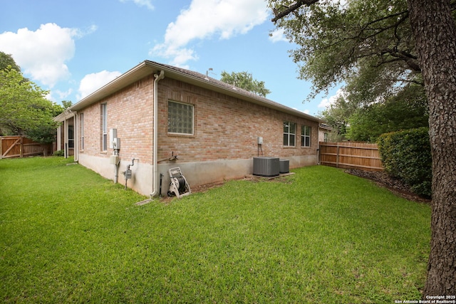 rear view of property with a lawn, a fenced backyard, and brick siding