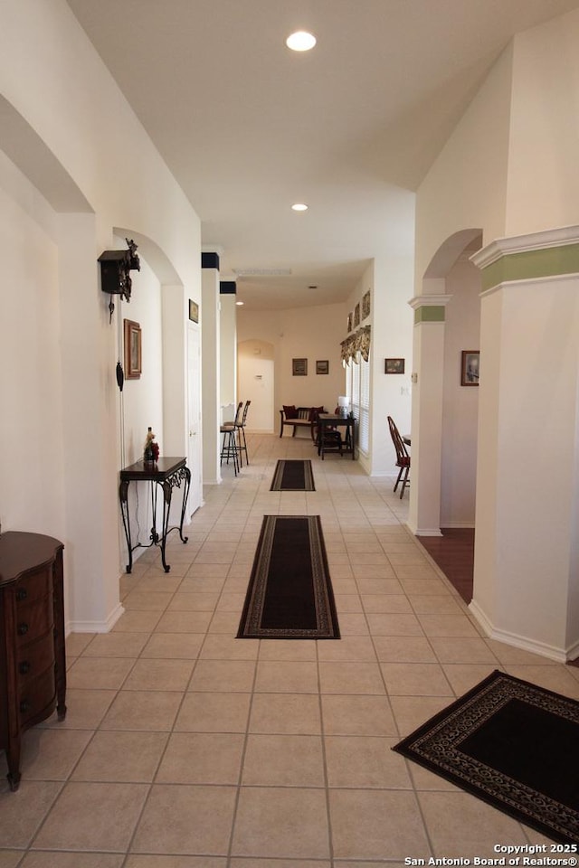 hall featuring arched walkways, recessed lighting, baseboards, and light tile patterned flooring