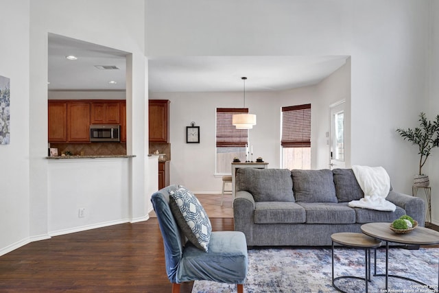 living room featuring visible vents, baseboards, and dark wood-type flooring