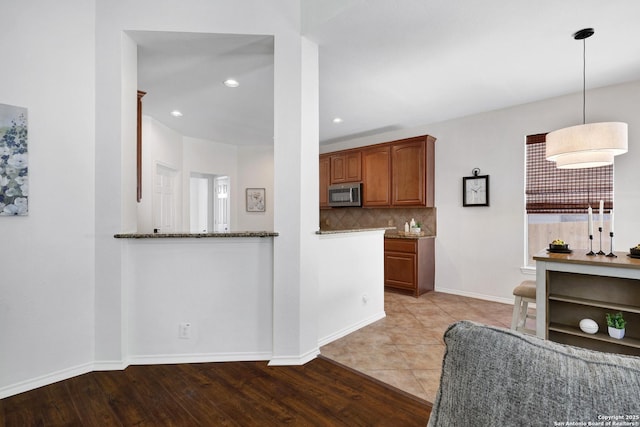 kitchen with stainless steel microwave, baseboards, tasteful backsplash, and light wood finished floors