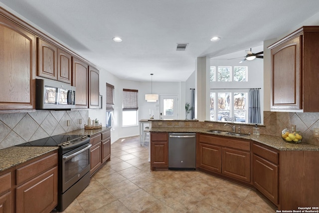 kitchen featuring visible vents, decorative light fixtures, dark stone counters, appliances with stainless steel finishes, and a sink