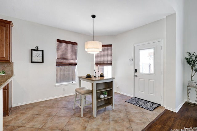 entryway featuring light tile patterned floors, baseboards, and plenty of natural light