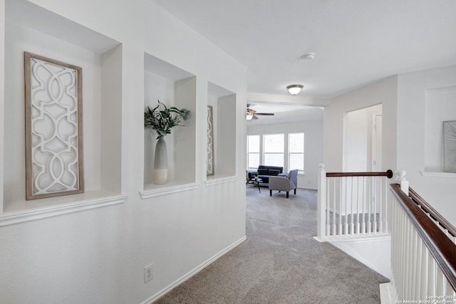 hall featuring an upstairs landing, carpet flooring, and baseboards