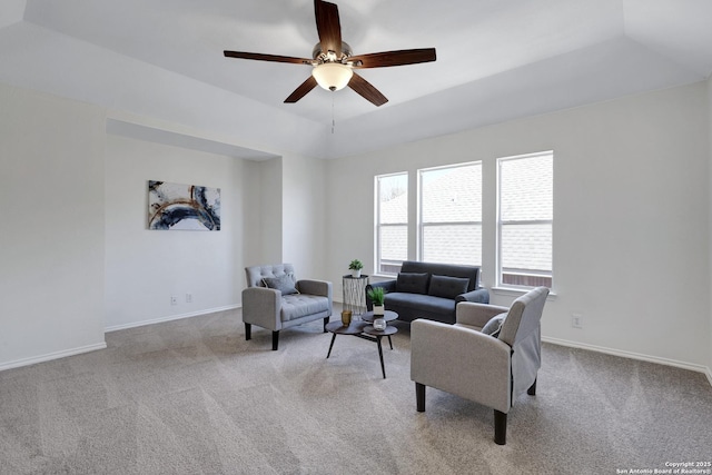 carpeted living room featuring ceiling fan, a tray ceiling, and baseboards