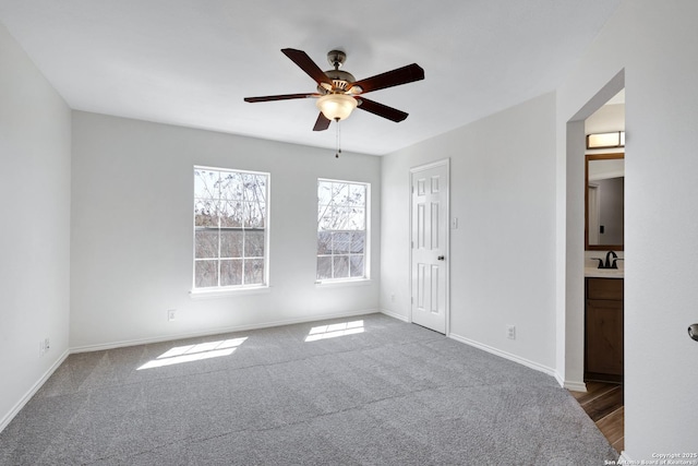 unfurnished bedroom featuring ensuite bathroom, a ceiling fan, carpet, and baseboards