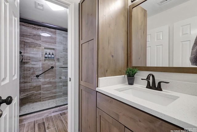 bathroom featuring vanity, visible vents, a tile shower, and wood finish floors