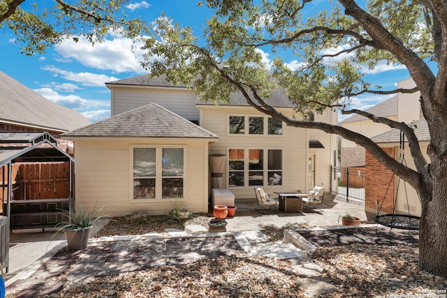 rear view of property featuring a patio area, fence, and a shingled roof