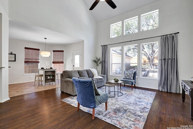 living area featuring dark wood-style floors, baseboards, a wealth of natural light, and high vaulted ceiling