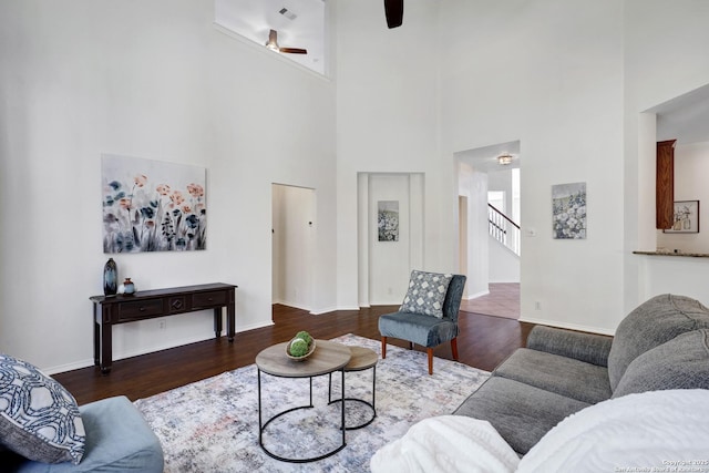 living area with ceiling fan, baseboards, wood finished floors, and stairs