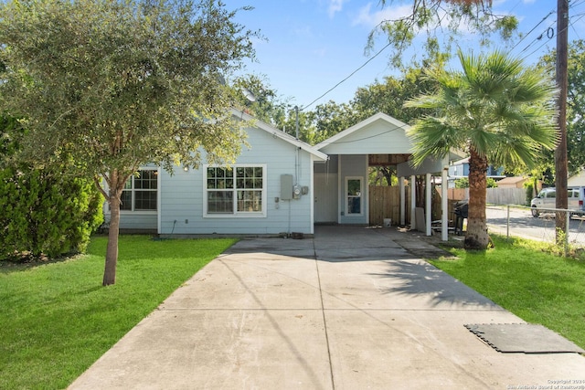 view of front of property with driveway, a carport, a front lawn, and fence