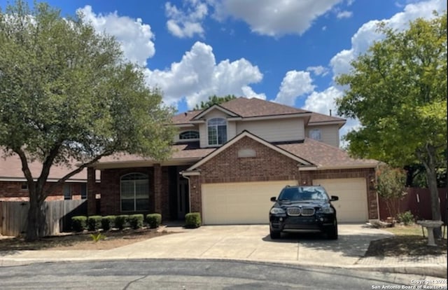 traditional home featuring brick siding, concrete driveway, an attached garage, and fence