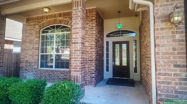 doorway to property with covered porch and brick siding